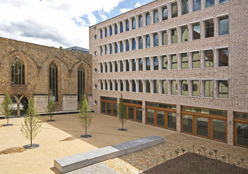 
Eine historische Kirchenwand mit ihren mittelalterlichen Bogenfenstern schließt unmittelbar an den Neubau an und schützt den attraktiven Innenhof.
