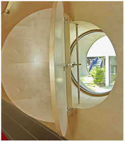 
Eine außergewöhnliche Verdunklung erfahren diese Rundbogenfenster: Zwei klappbare Holzläden sind an einer Drehstange in der Mitte des Fensters befestigt.
