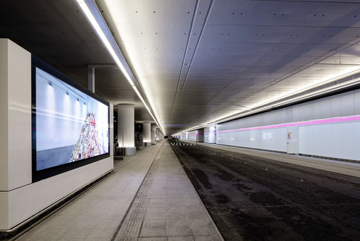 Multimedialer Erlebnisraum: Neben den leuchtenden Wänden, gibt es sechs großformatige LED-Flächen für Flughafen­werbung. Letztere werden durch das Lichtband in der Terminal-Fassade farblich unterstützt. - © Jörg Hempel, Aachen
