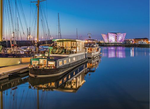 



Nachts fällt der Blick durch die großen Fenster auf das spektakulär erleuchtete Schifffahrtsmuseum „Titanic Belfast“.
