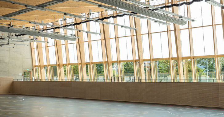 Geräumige Turnhalle mit großen, holzgerahmten Fenstern, die natürliches Licht hereinlassen. - © TA, Architektur: mvm+starke, Architektur: bharchitekten