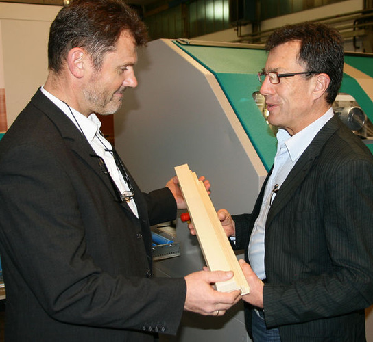 Marketingleiter Michael Mühldorfer (l.) bei der Demonstration der Oberflächengüte von mit Q-Fin behandelten Holzkanteln. - Daniel Mund / glaswelt.de