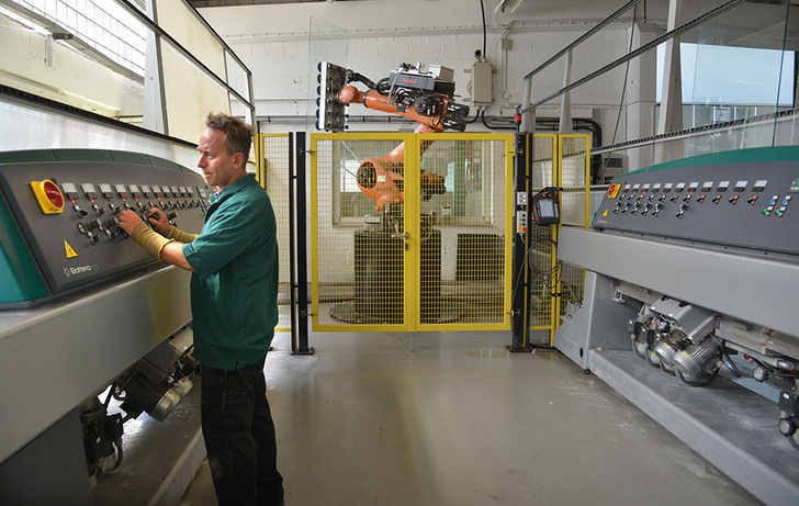 Konsequente Automation: Ein Roboter versetzt die Scheiben an einem Schleifautomaten. Das verbessert den Durchsatz, ist rückenschonend und trägt zur hohen Produktqualität bei. - A+W