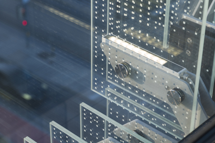 Die Glaslamellen, bedruckt mit weißen Quadraten, reflektieren das Licht und sorgen nachts für einen unwirklichen Lichteffekt in der Fassade. - Erco GmbH, www.erco.com, Fotografie: Moritz Hillebrand