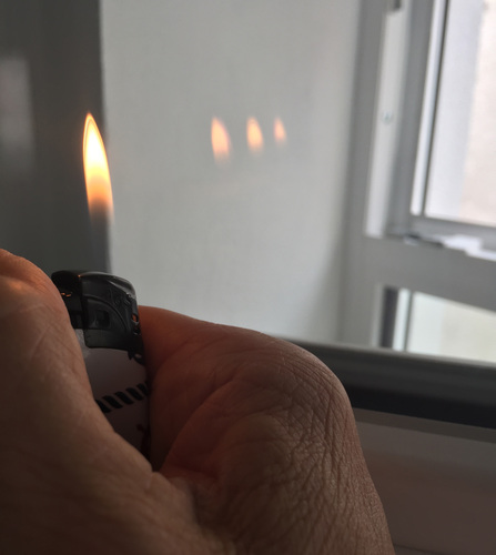Mit einem einfachen Feuerzeug lässt sich die Zahl der Scheiben und Beschichtungen in einem Fenster ermitteln (das geht natürlich auch mit einer Kerze...) - Daniel Mund / GLASWELT - © Daniel Mund / GLASWELT

