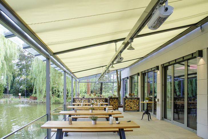 Für den Sonnenschutz sorgt die untergesetzte Wintergartenmarkise Sottezza II ­OptiStretch. Zur Seite schließt das Terrassendach mit einer Glasschiebetür ab. Der Baum wurde ins Glas integriert. - Weinor