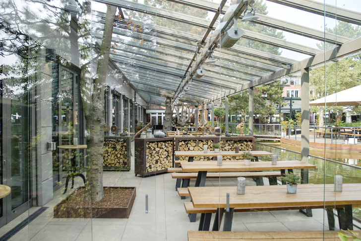 Zur Seite schließt das Terrassendach mit einer Glasschiebetür ab. Der Baum wurde ins Glas integriert. - Weinor