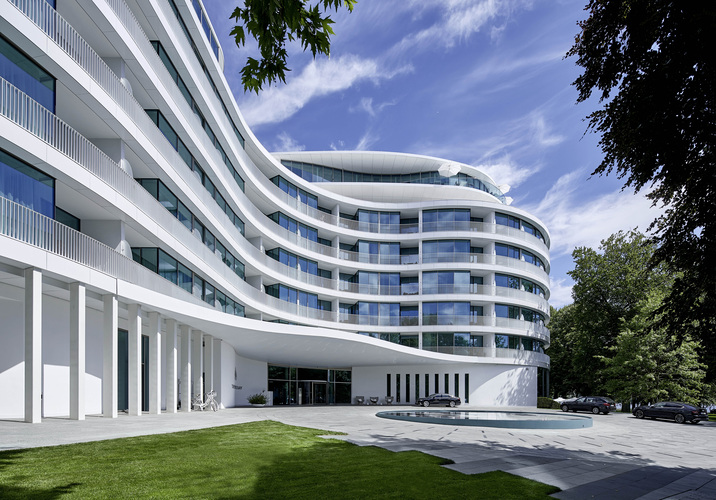 Horizontale Bänder aus Glas und schneeweiß glasierte Kera-mikplatten im Großformat wickeln sich wie an einem endlos wirkenden Band um das Gebäude. - Jochen Stüber