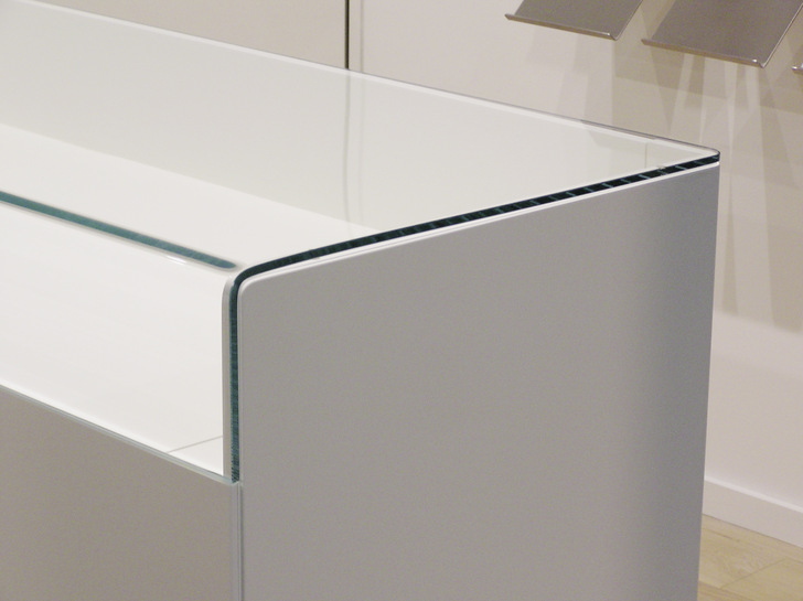Elegant gelöst ist bei dieser Vitrine die Oberseite, bei der das Glas via 90° Winkel in den Frontbereich übergeht.