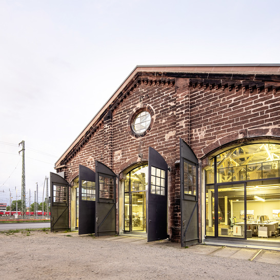 Sandsteinmauern, verblechte Tore un﻿d raumhohe Industrieverglasungen in Stahlrahmen kennzeichnen den komplett sanierten Lokschuppen. - © Foto: Daniel Vieser, Hildesheim und Karlsruhe / Jansen AG
