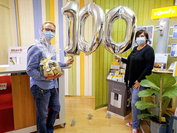 Die feierliche Eröffnung des 100. Somfy Experten-Onlineshops ließ sich auch Kathrin Härtel nicht entgehen. Unter den gebotenen Corona-Regeln überreichte die Außendienstmitarbeiterin von Somfy drei große Ballons in Form der Zahl 100 sowie einen Geschenkkorb in Leisnig an Andreas Schmidt.