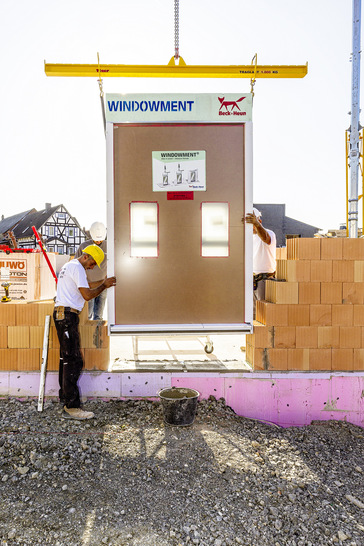 Einsetzen des Fenster-Komplettelements in teilweise aufgemauerte Außenwände mittels Kran - © Foto: Beck+Heun
