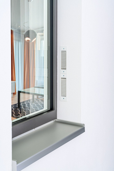 Das Zwei-Wege-Lüftungsgerät „Caire smart“ wird ins Fenstersystem integriert (seitlich oder oben, mit sichtbarem, farblich angepasstem Gehäuseprofil) und kann überdämmt und überputzt werden.