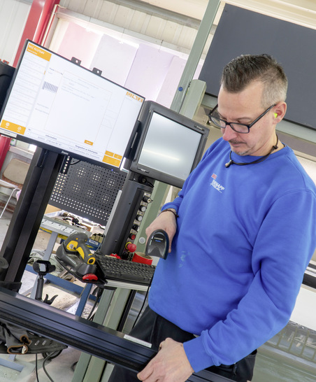Metallbauer Sascha Günther scannt den Barcode eines Profils. So kommt das Bauteil ins System.