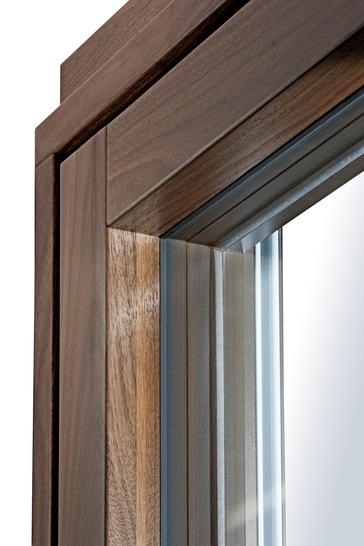 Neu von Kneer-Südfenster sind Aluminium-Holz-Fenster mit flächenbündigem Design und verdeckt liegenden Beschlägen, bei denen Rahmen und Flügel auf einer Ebene liegen – besonders elegant in der Holzart Nussbaum.