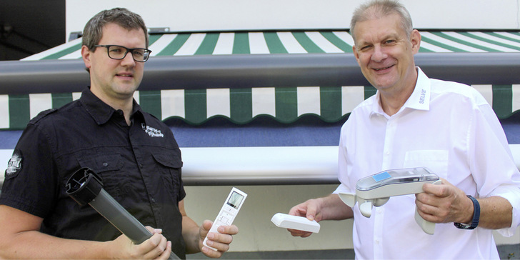 Aus bislang zwei Produkten wird eins: Der neue SE Breeze-RC, den Entwickler Andreas Werner (li.) präsentiert, punktet mit einer leichten Einstell- und Bedienphilosophie. Mittels Funkhandsender lassen sich die Schwellwerte des integrierten Windschutzes komfortabel einstellen. Zusätzliche Windsensoren, wie sie hier Dirk Wrobel (Produkt­manager textiler Sonnenschutz) zeigt, werden durch die einzigartige Antriebslösung nicht mehr benötigt.