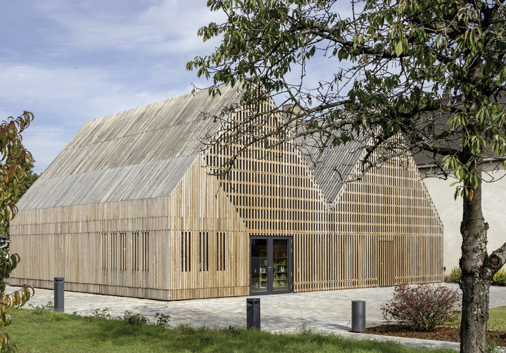 Spektakulär in Szene gesetzt. Von der Form her den Hofgebäuden des 18. Jahrhunderts nachempfunden, sind beide Neubauten komplett mit Eschenlatten verschalt. Semco Energy-Gläser sorgen in der Fassade dahinter für den Klimaschutz. - © Foto: Stefan Meyer
