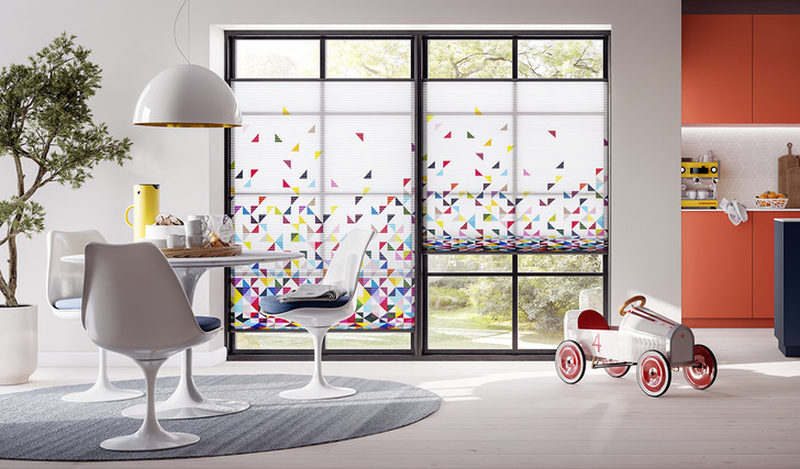 Bunte Dreiecke wirbeln wie Flugsamen durch die Luft: Duette Wabenplissees Dessin Earth, aus der Themenwelt „Elements by sieger design“.