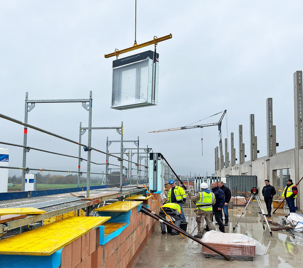 Mit einem Kran werden die kompletten Fenster auf der Baustelle an die Einbaustelle transportiert.