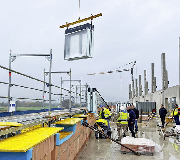  Mit einem Kran werden die kompletten Fenster auf der Baustelle an die Einbaustelle transportiert.