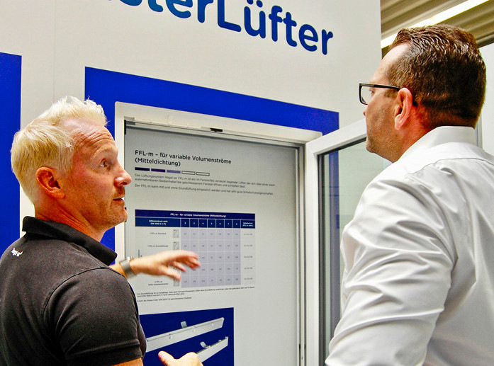 Thomas Verhoeven (l.), Geschäftsführer bei Regel-air, erklärt Denis Fellner im Showroom am nieder­rheinischen Firmensitz die unterschiedlichen Funktions­weisen der verschiedenen Fensterfalzlüfter.
