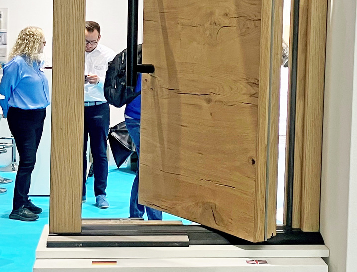 Bei der von Alumat vorgestellten Lösung lässt sich bei einer Pivot-Tür das Drehlager in der Schwelle versenken und mithilfe der Polyamid-Deckel in der Länge verschiebbar positionieren.