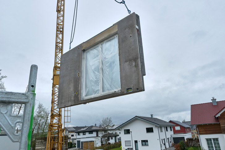 Per Kran werden die hoch vorgefertigten Betonwände auf der Baustelle montiert. Fenster, Dämmung und technische Vorinstallationen sind bereits integriert.