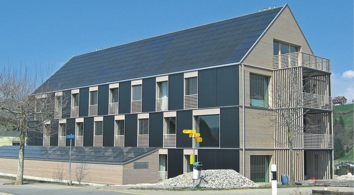 Mehrfamilienhaus in Bennau (CH): Das Dach ist mit Photovoltaikmodulen voll­flächig belegt, zudem wurden in der Fassade ­solar­thermische Kollektoren integriert.