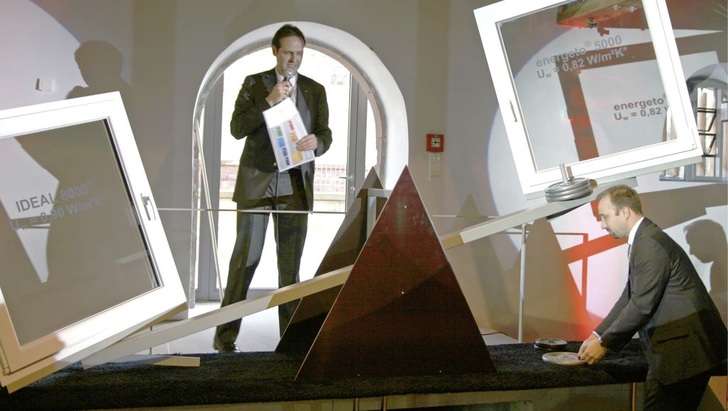 Patrick Seitz erläutert die Waage: Auf der einen Seite das energeto 5000 mit VIG und auf der anderen Seite das energeto 8000 mit konventionellem 3-fach ISO. Andreas Heilig legt als Ausgleich die Gewichte auf.