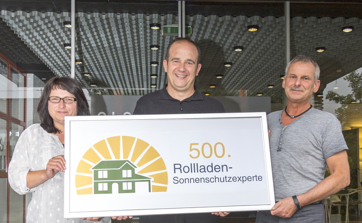 Überraschungsgäste bei elero: Marion Hare (Fa. Frey) und Jürgen Graf (Fa. Dech) besuchten Hermann Sonntag, Techniker und Schulungsleiter bei elero (Bildmitte) an seinem Arbeitsplatz. Grund: Er ist das 500. Mitglied ihrer erfolgreichen Facebook-Gruppe Rollladen-Sonnenschutzexperte und bekam daher persönlich ein Zertifikat überreicht.