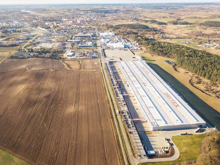 Der zweite Teil des neuen Produktionsareals ist bei der Luftaufnahme ganz im Vordergrund zu erkennen. Weiter hinten stehen die alten Produktionshallen.