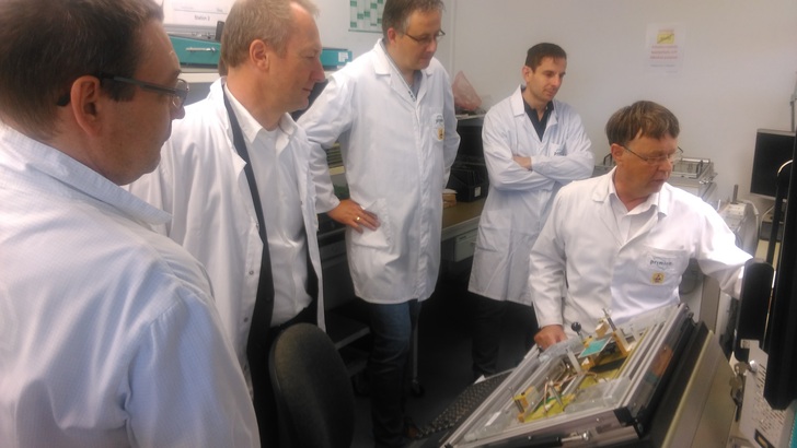 Produktionsleiter Albrecht Dietrich (r.) erläutert den Teilnehmern den Incircuit-Tester.