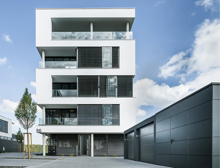 



Der Wechsel aus weißen Putzflächen und dunkel abgesetzten Fensterbändern verleiht den Baukörpern schon von Weitem ein skulpturales Erscheinungsbild.
