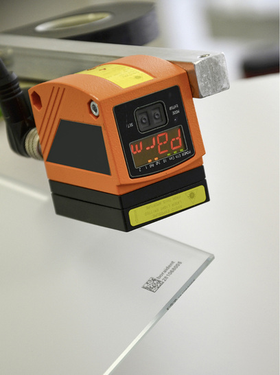 <p>
Mit dem Unicolor-Laserdruckverfahren lassen sich Gläser dauerhaft und kratzfest markieren, ohne dass die Oberfläche beschädigt wird. Dies erlaubt die Nachverfolgung mittels Scanner (orange im Bild) über den gesamten Fertigungsprozess. 
</p>

<p>
</p> - © Foto: Hegla

