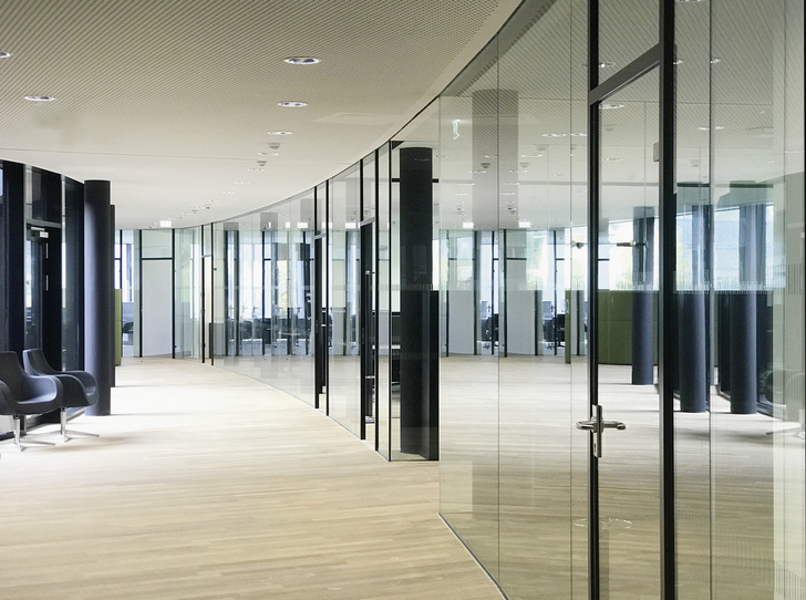 Die äußere Gebäudeform sowie die Innenräume sind geprägt von oval ­verlaufenden Wandflächen. Im Gebäude kommt das flexible Längle Glastrennwand-System ­AL-­Office XL zum Einsatz. - © Osswin Längle
