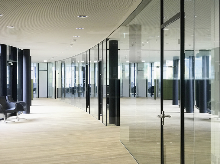 Die äußere Gebäudeform sowie die Innenräume sind geprägt von oval ­verlaufenden Wandflächen. Im Gebäude kommt das flexible Längle Glastrennwand-System ­AL-­Office XL zum Einsatz.