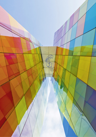 



Das Fensters zur Welt hat eine farbenfrohe Fassade aus VSG-Scheiben in roten, gelben, grünen, blauen und weißen Schattierungen, die in einem Harlekinmuster arrangiert sind.
