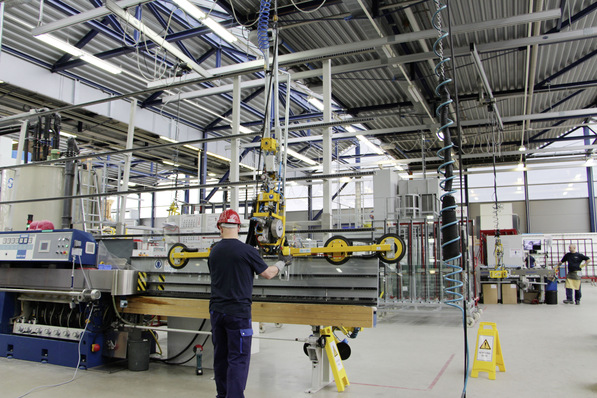 Im Bild: Der Bediener bewegt erstmals eine etwa 4500 × 700 mm große Glasscheibe und stellt diese auf das Band der Schleifmaschine.