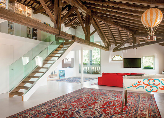 Das stattliche Wohn- und Esszimmer ist das Herzstück des Lofts mit einer Treppe in Glas und Holz. Durch den Einsatz der wandbündigen Flügeltüren von Eclisse gelingt es, ­Türen und Wände als einheitliche Fläche zu gestalten.