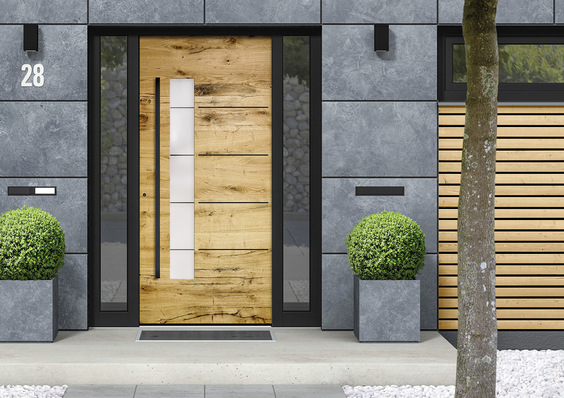 Das natürlich gewachsene Eichenholz kombiniert sich mit tiefschwarzen Rahmen, ­Lisenen und Griffstange zu einer modern gestalteten Haustür.