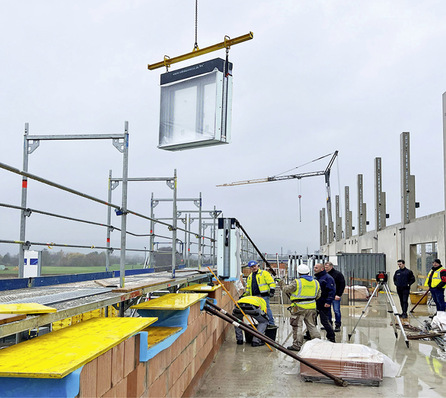  Mit einem Kran werden die kompletten Fenster auf der Baustelle an die Einbaustelle transportiert.