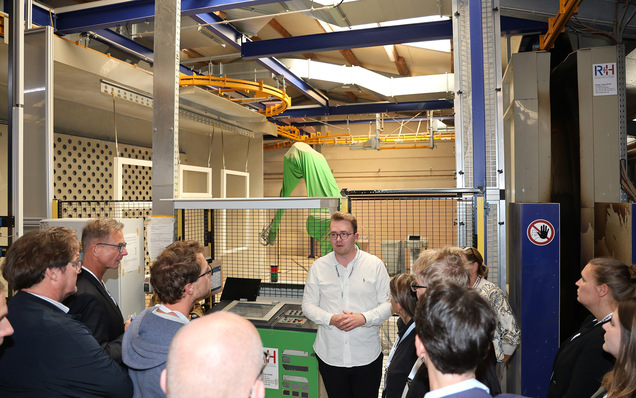 Simon Hinrichs erläutert beim Werksrundgang den Farbauftrag von Sikkens Wood Coatings Lacken und Lasuren per Spritzroboter.