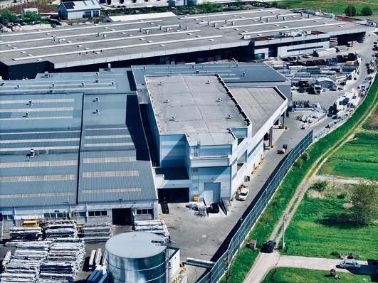 Das Hochregallager (vorne rechts) schließt direkt an die Gebäude für Produktion und Versand an. Damit bleiben die Wege kurz und die Effizienz wird gesteigert.