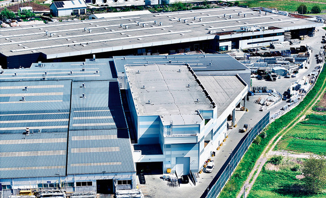 Das Hochregallager (vorne rechts) schließt direkt an die Gebäude für Produktion und Versand an. Damit bleiben die Wege kurz und die Effizienz wird gesteigert.