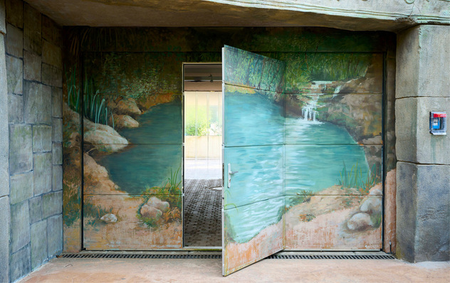 Individuell bemalt fügt sich das ­Sektionaltor SW 40 mit Schlupftür ­ebenso wie ein Teil der Innen- und ­Außentüren gut in die tropische Kulisse aus Wasser, Pflanzen und Steinen ein.