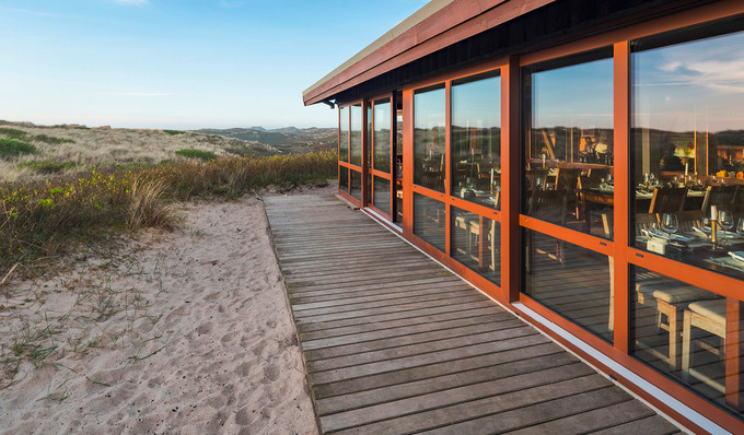 Besondere Herausforderungen der Sanierungsmaßnahmen der „Sansibar“ auf Sylt waren bauordnungsrechtliche Vorschriften zum Küsten- und Dünenschutz sowie ein ausreichender Schutz gegen Wind und ­Wetter.Im Bild: Hebe-Schiebesystem Schüco ASE 80.HI.