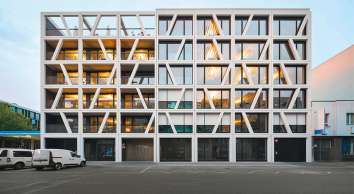 Die hell erleuchteten Arbeits- und Produktionsräume kommunizieren über das Fassadenrelief und projizieren ein gemeinsames Bild ihrer vielfältigen Nutzung.