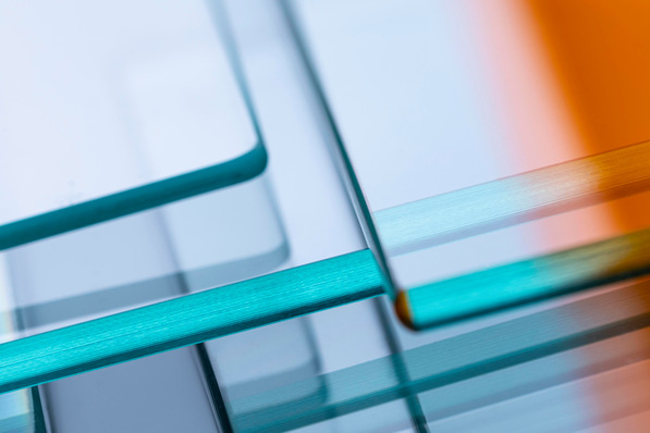 Optimierter Alt-Text: Detailaufnahme mehrerer überlappender Isolierglasscheiben mit Antireflexbeschichtung, die farbige Lichtreflexe zeigen; typische Anwendung in energieeffizienten Fassadensystemen und moderner Fenstertechnik. - © Glaston