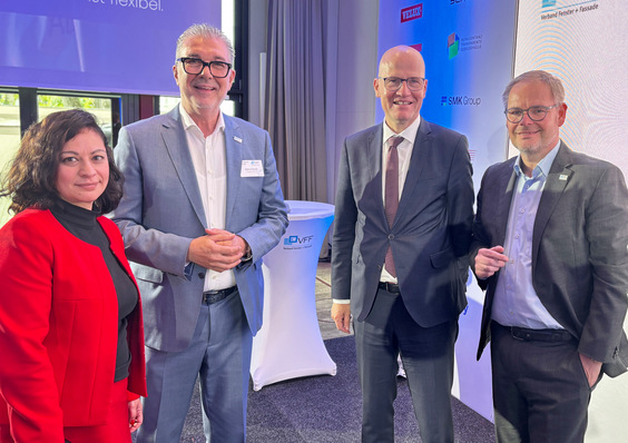 Gerne, hier ist ein optimierter Alt-Text, der den Fachkontext und die Zielgruppe berücksichtigt: Alt-Text: „Vier Branchenexperten aus Fenster-, Fassaden- und Glastechnik vernetzen sich auf einer Fachmesse vor einem Präsentationsstand mit innovativen Lösungen für Gebäudehülle und Sonnenschutz.“ Begründung: Der Alt-Text beschreibt die abgebildeten Personen als Fachleute aus den relevanten Bereichen (Fenster, Fassade, Glas), nennt explizit das Branchenevent (Fachmesse) statt allgemein „Business Event“, sowie den Bezug zu Innovationen in Gebäudehülle und Sonnenschutz – allesamt zentrale Themen für Ihre Leser:innen. - © Daniel Mund / GW
