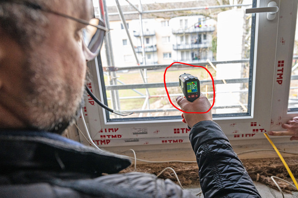 Ein Techniker misst die Temperatur eines eingebauten Heizglas-Fensters.